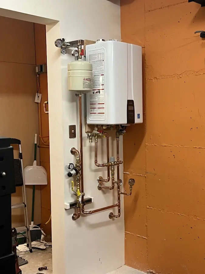 Plumbing technician inspecting water heater connections in Boonville